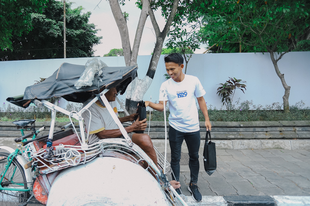 Sugiyanto berbagi nasi bungkus kepada tukang becak yang sedang beristirahat.